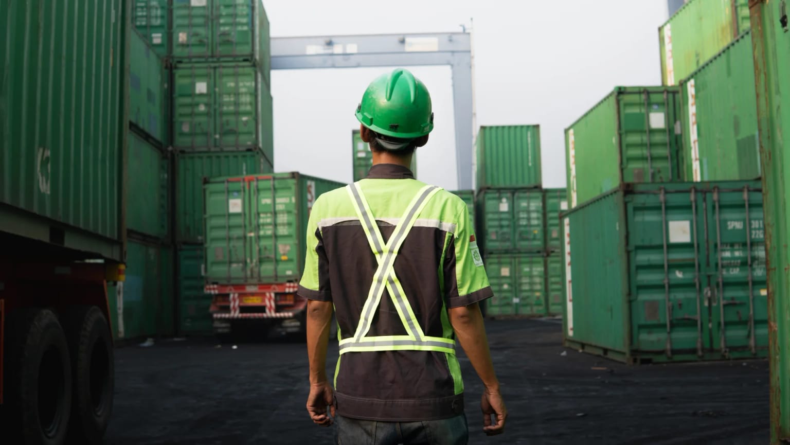 BSB worker in helmet and hi-vis vest facing stacked containers